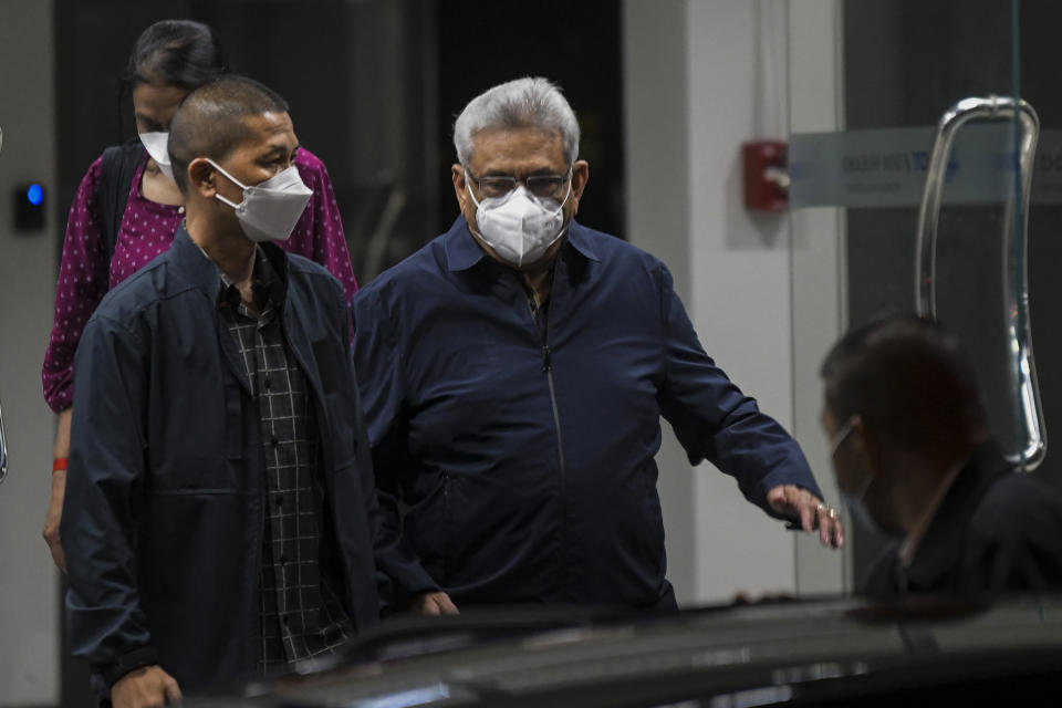 Former Sri Lankan President Gotabaya Rajapaksa, center, walks to a waiting vehicle outside the Don Mueaung airport in Bangkok, Thailand Thursday, Aug. 11, 2022. Rajapaksa, who last month fled anti-government protests in his country, has left Singapore, immigration authorities there said Thursday. (AP Photo/Tananchai Keawsowattana)