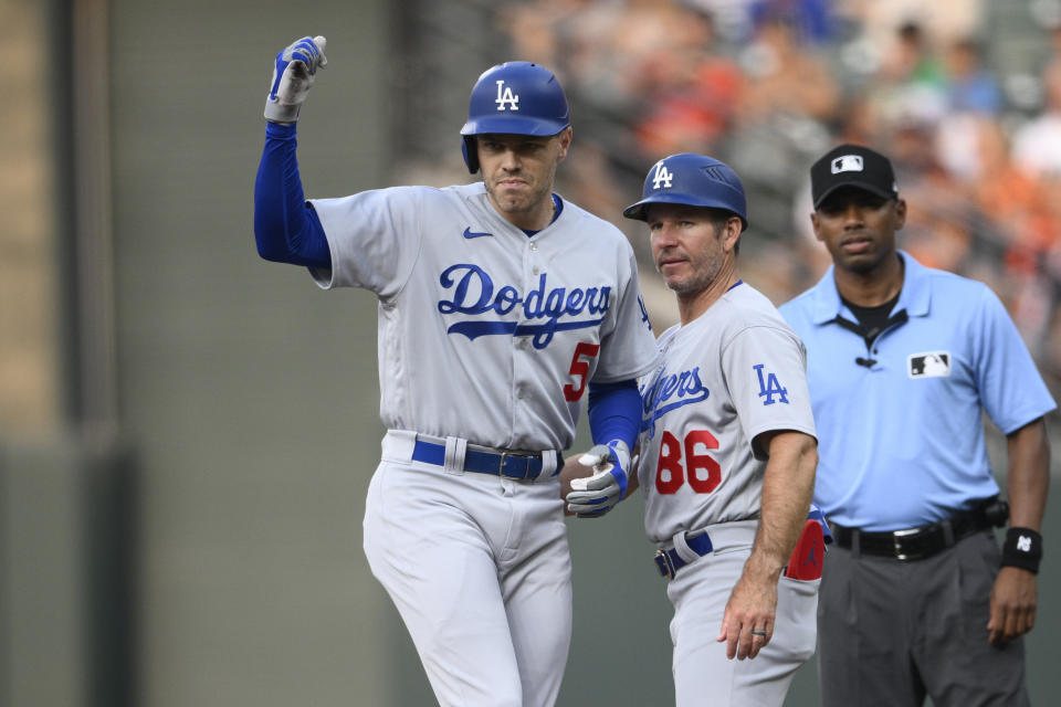 Los Angeles Dodgers' Freddie Freeman (5) gestures next to first base coach Clayton McCullough (86) after he singled during the first inning of a baseball game against the Baltimore Orioles, Tuesday, July 18, 2023, in Baltimore. (AP Photo/Nick Wass)