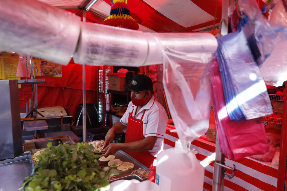 Biodegradable plastic bags, in compliance with a 2020 plastic bag ban, hang at a taco stand in central Mexico City, Friday, Jan. 1, 2021. The few street food vendors out working on New Year's Day amid the COVID-19 pandemic said they were either unaware of or were still figuring out how to comply with a broad ban on single-use containers, forks, straws, and other ubiquitous items that took effect Friday in Mexico's capital, one of the world's largest cities, after more than a year of preparation. (AP Photo/Rebecca Blackwell)