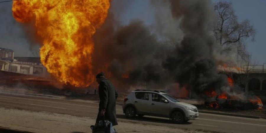 A man in Kharkiv walks past a fire after shelling, March 25, 2022