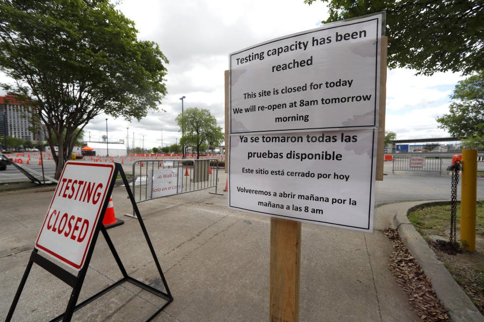 Signs placed outside a barricaded entrance to a coronavirus testing location state the location is closed for the day in Dallas, Tuesday, March 31, 2020. (AP Photo/Tony Gutierrez)