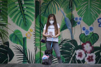 A woman takes a picture of her dog outside the Eastwood mall in Quezon city, Philippines as government eases restrictions after a decline in Coronavirus cases in the country on Thursday, Oct. 14, 2021. Several businesses were allowed to reopen in the next days as the country tries to revive the economy which have suffered due to lockdowns to prevent the spread of COVID-19. (AP Photo/Aaron Favila)