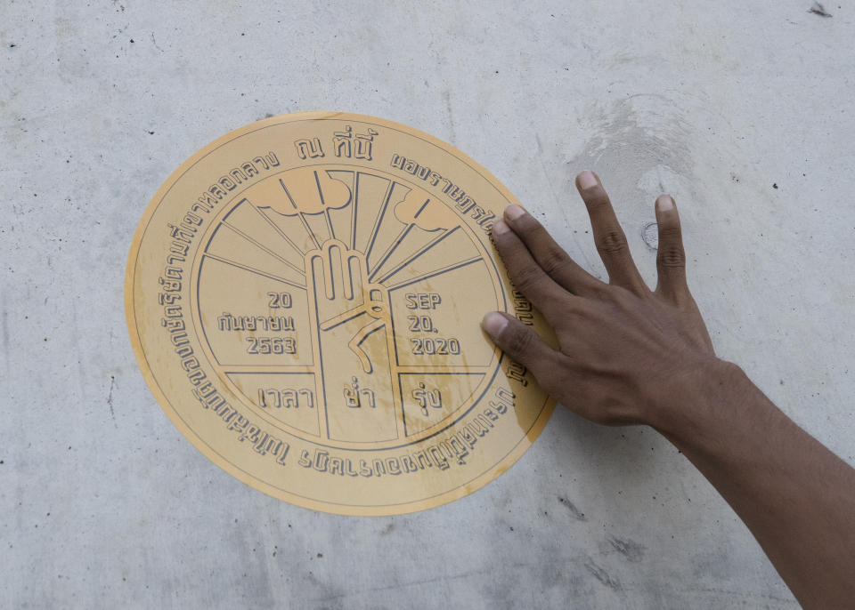 Pro-democracy protester Panupong Jadnok pastes a sticker of a plaque marking Thailand's transition to democracy on the wall of Parliament during a protest in Bangkok, Thailand, Thursday, Sept. 24, 2020. Lawmakers in Thailand are expected to vote Thursday on six proposed amendments to the constitution, as protesters supporting pro-democratic charter reforms gathered outside the parliament building. (AP Photo/Sakchai Lalit)