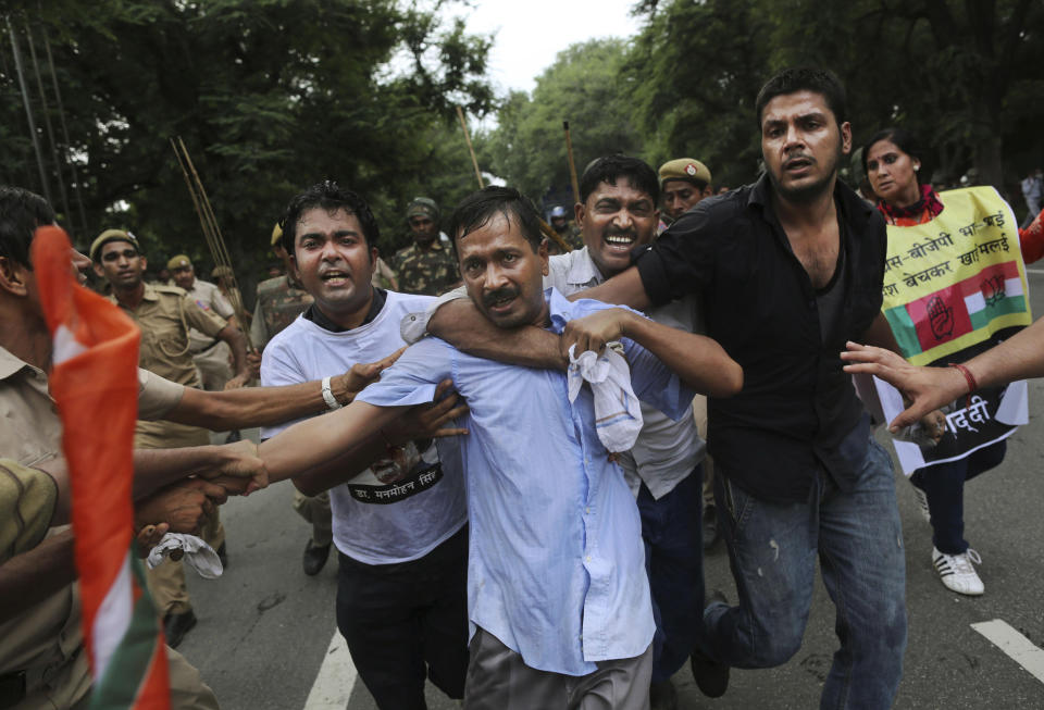 FILE – In this Sunday, Aug. 26, 2012 file photo, Indian anti-corruption activist Arvind Kejriwal, center, is shielded by supporters as he flees police during clashes at a protest near the Prime Minister's official residence in New Delhi, India. Launching his own political party this month, longtime bureaucrat-turned-activist Kejriwal taps into the disgust of ordinary Indians amid a seemingly unending stream of corruption scandals that have tainted politicians of all stripes over the last few years. (AP Photo/Kevin Frayer, File)