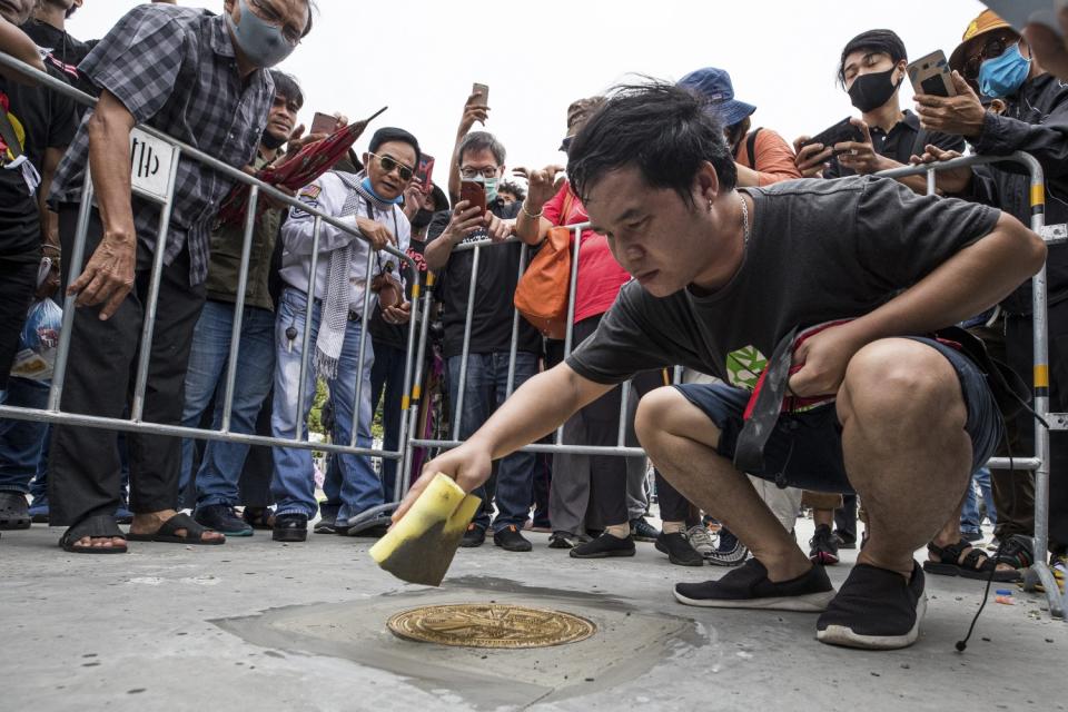 A Thai democracy supporter affixes a plaque to the floor of a Bangkok plaza.