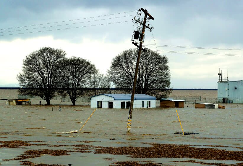 LEMOORE, CALIF. - MAR. 21, 2023. Floodwaters from a break in in levees in the vast and fertile San Joaquin Valley floods structures of a farming operation near Corcoran. Snowmelt from heavy snowfall in the mountainns that ring the valley are expected to excacerbate local flooding with the advent of spring. Tulare Lake, a body of water that was largely drained more than 100 years ago, has been filling up after a series of powerful storms that have struck California this winter. (Luis Sinco / Los Angeles Times)