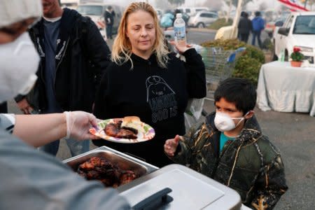 After losing their home in Magalia in the Camp Fire, Robin Tompkins and her son, Lukas, line up for a free meal in a makeshift evacuation center in Chico, California, U.S., November 16, 2018.  REUTERS/Terray Sylvester