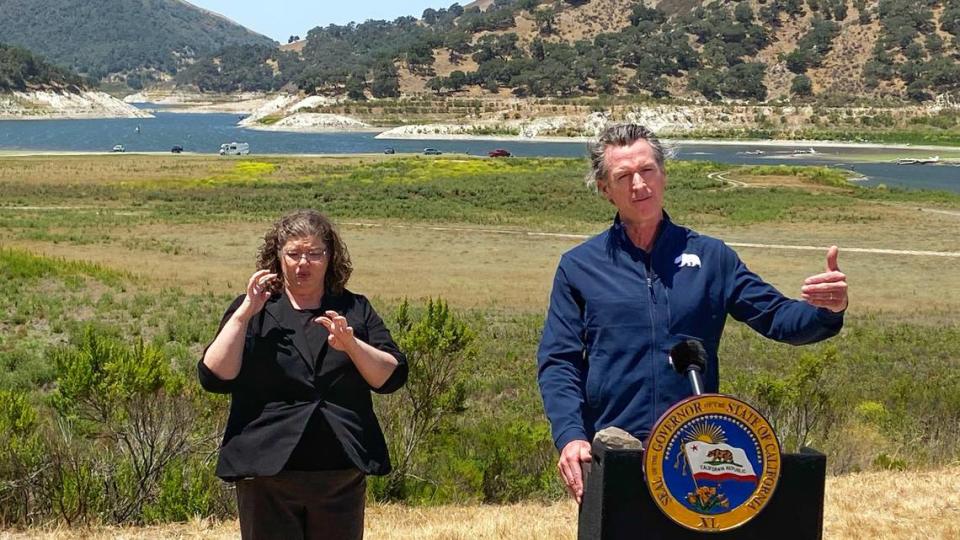 Gov. Gavin Newsom and interpreter Julia Townsend stand at the edge of a diminished Lopez Lake near Arroyo Grande. The lake was at 34.7% capacity and the governor asked the state to save water. Lopez Lake provides drinking water to the Five Cities community of Arroyo Grande, Avila Beach, Grover Beach, Oceano and Pismo Beach on Monday, July 8, 2021.