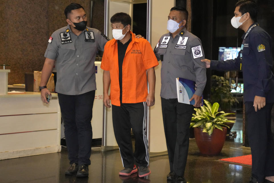 Immigration officers escort Japanese fugitive Mitsuhiro Taniguchi, center, who was arrested on Sumatra island in early June, prior to his deportation in Jakarta, Indonesia, Wednesday, June 22, 2022. Indonesia on Wednesday deported Taniguchi who was wanted by Japanese police for COVID-19 subsidy fraud. (AP Photo/Dita Alangkara)