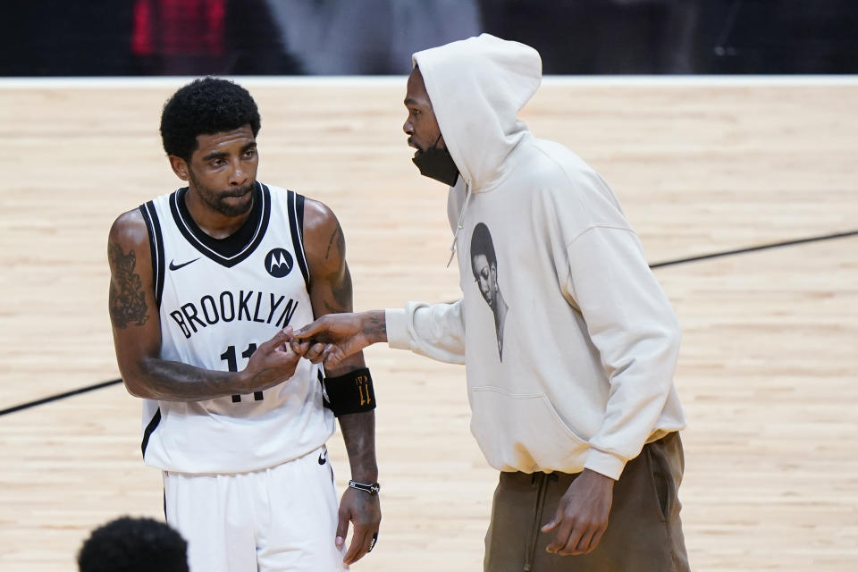 Brooklyn Nets forward Kevin Durant, right, talks with guard Kyrie Irving during a time out in the second half of an NBA basketball game against the Miami Heat, Sunday, April 18, 2021, in Miami. Durant was forced to leave the game early in the first quarter with a left thigh injury. (AP Photo/Wilfredo Lee)