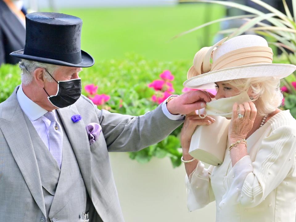 Then-Prince Charles helps Camilla Parker Bowles with her mask at the Royal Ascot in 2021.