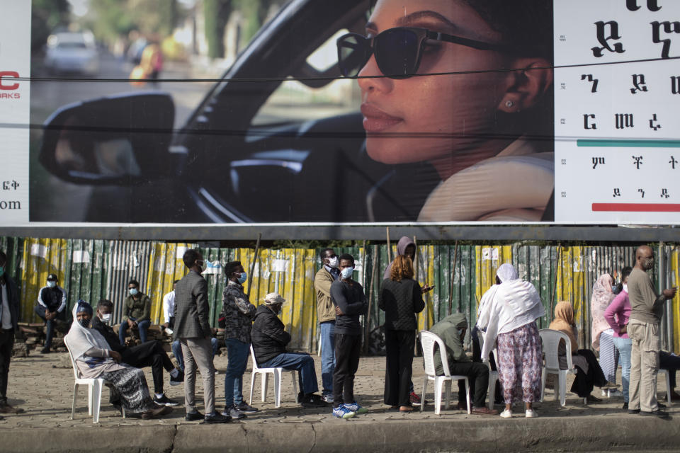 Ethiopians queue on chairs in the street, underneath a billboard for an eye clinic, as they wait to cast their votes in the general election at a polling center in the capital Addis Ababa, Ethiopia Monday, June 21, 2021. Ethiopia was voting Monday in the greatest electoral test yet for Prime Minister Abiy Ahmed as insecurity and logistical issues meant ballots wouldn't be cast in more than 100 constituencies of the 547 across the country. (AP Photo/Ben Curtis)