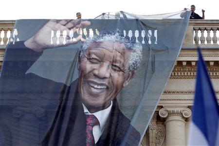 Workmen unfurl a giant banner with a photo of the late South African President Nelson Mandela to cover the facade of the Quai d'Orsay Foreign Affairs Ministry in Paris, December 6, 2013. South African anti-apartheid hero Mandela died peacefully at home in Johannesburg at the age of 95 on Thursday after months fighting a lung infection, leaving his nation and the world in mourning for a man revered as a moral giant. REUTERS/Charles Platiau