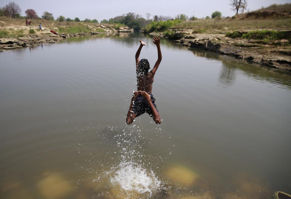 In this April 15, 2014 photo, a boy baths in the Kelo River, where little black coal nuggets now populate the riverbed, in Gare village, near the industrial city of Raigarh, Chhattisgarh state, India. Villagers say the coal mine dumps waste water into the river at night. (AP Photo/Rafiq Maqbool)