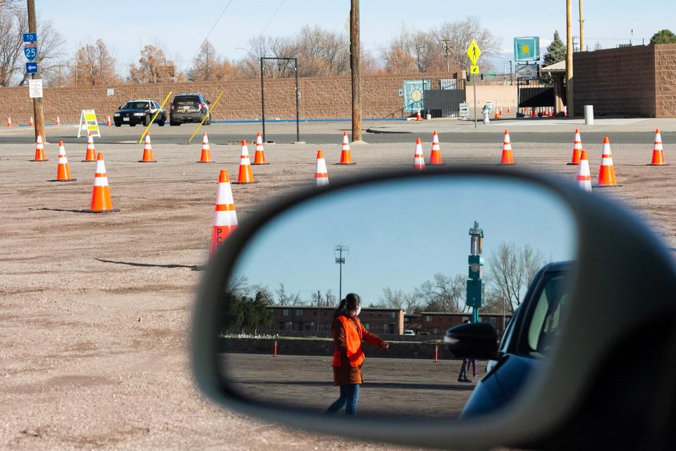 A volunteer waves forward cars arriving on Friday, March 26 at the Colorado State Fairgrounds for COVID-19 vaccinations.