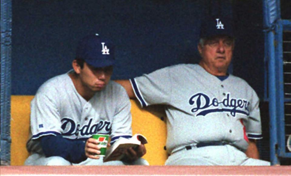 Dodgers pitcher Hideo Nomo reads a book as manager Tom Lasorda watches a 1995 game in Montreal.