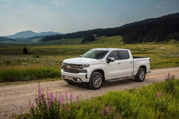 A white Chevy Silverado pickup driving on a rural road