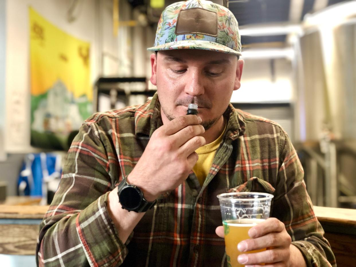 Greater Goods' Chris Zampa sniffs a sample of the terpene used in Dank Pulp Daddy before taking a sip of the beer.