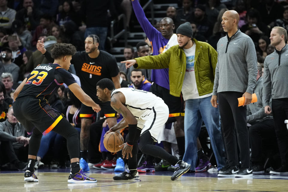 Brooklyn Nets guard Kyrie Irving looks to pass as Phoenix Suns forward Cameron Johnson (23) defends during the second half of an NBA basketball game, Thursday, Jan. 19, 2023, in Phoenix. (AP Photo/Matt York)