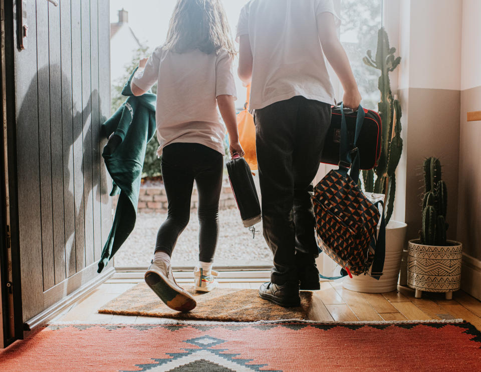 kids leaving the house carrying bags