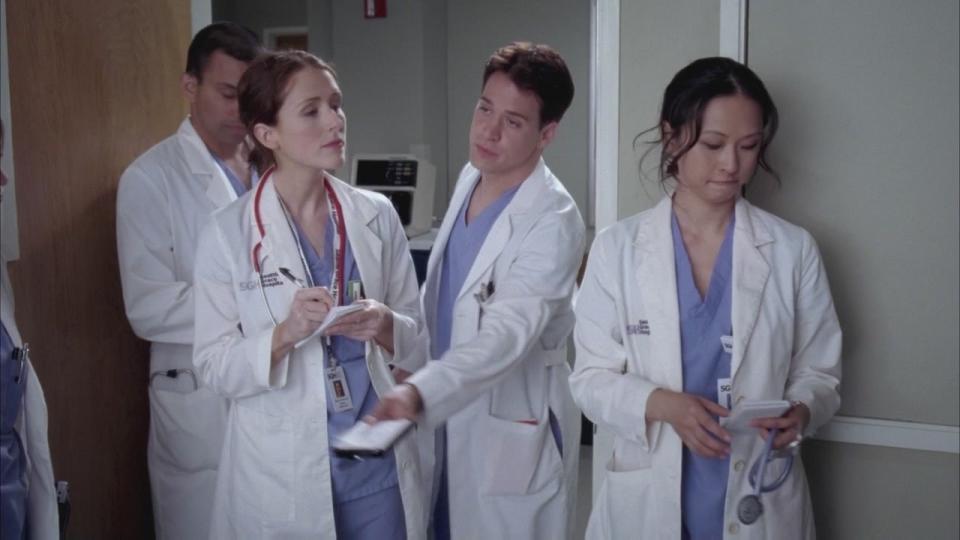 A Grey's Anatomy screen cap showing George and three other interns, he is passing a notebook to someone