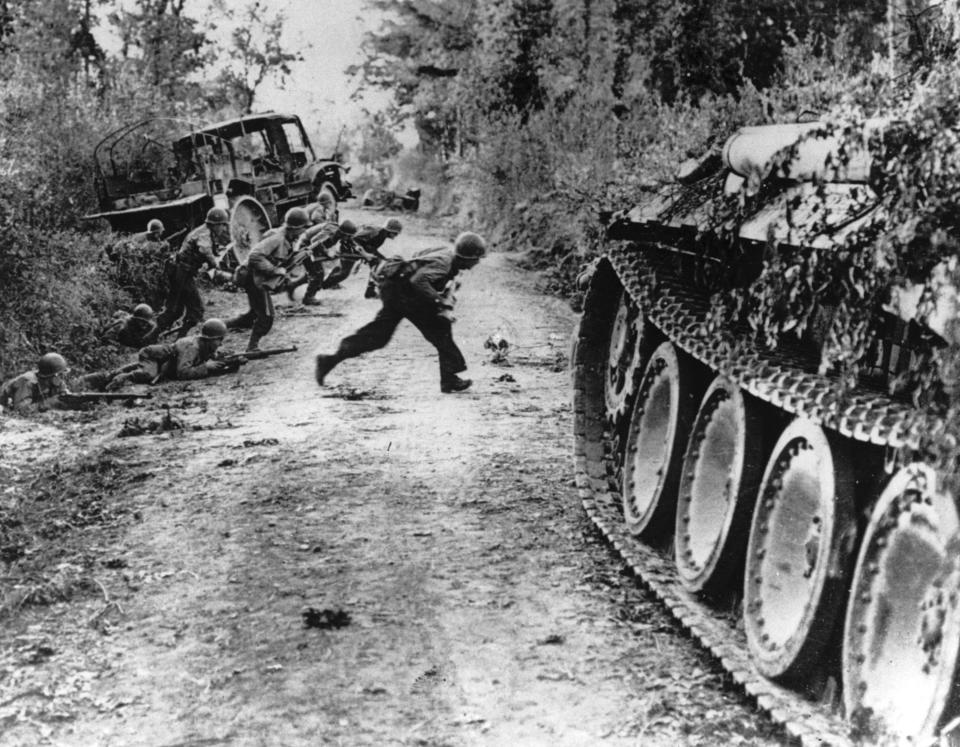 FILE - During the Allied invasion of the Normandy region in France, American soldiers race across a dirt road while they are under enemy fire, near St. Lo, in July 1944. (Pool via AP, File)