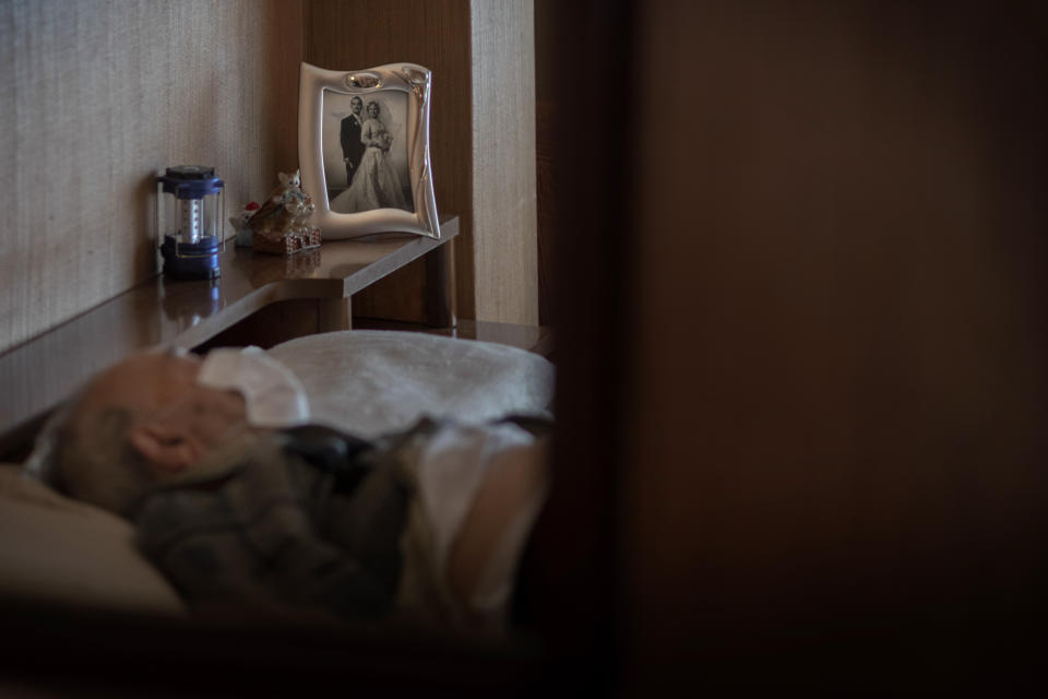 Leopoldo Roman, 85, lies in bed wearing a face mask as he waits for doctors during a home medical visit in Barcelona, Spain, April 3, 2020. Roman, whose leg was amputated years ago, has to pay for daily care out of his pension since the public system only provides for a social worker to come for an hour a day, three days a week. (AP Photo/Emilio Morenatti)