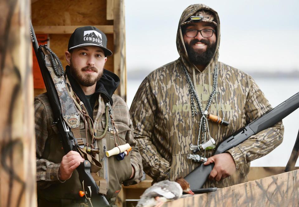 Waterfowl hunters Jason Peterson, left, and Donovan DeBoe, both 27, wait in a blind overlooking Presque Isle Bay near Erie on Nov. 8. The friends were introduced through the sport and spent a recent morning spotting geese and ducks, downing a few flying within range, such as the common merganser, foreground.