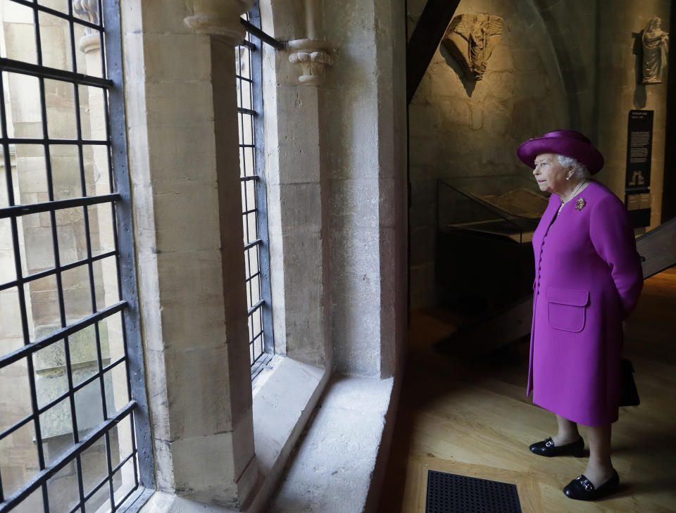 FILE - Britain's Queen Elizabeth II, looks through a window at the view as she walks through The Queen's Diamond Jubilee Galleries at Westminster Abbey in London, Friday, June 8, 2018. Britain is getting ready for a party featuring mounted troops, solemn prayers — and a pack of dancing mechanical corgis. The nation will celebrate Queen Elizabeth II’s 70 years on the throne this week with four days of pomp and pageantry in central London. (AP Photo/Kirsty Wigglesworth, Pool, FIle)