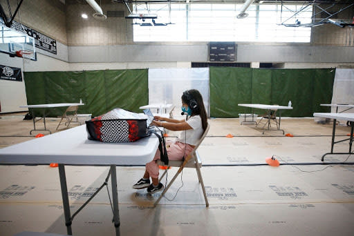 A student works at a desk alone in a large room