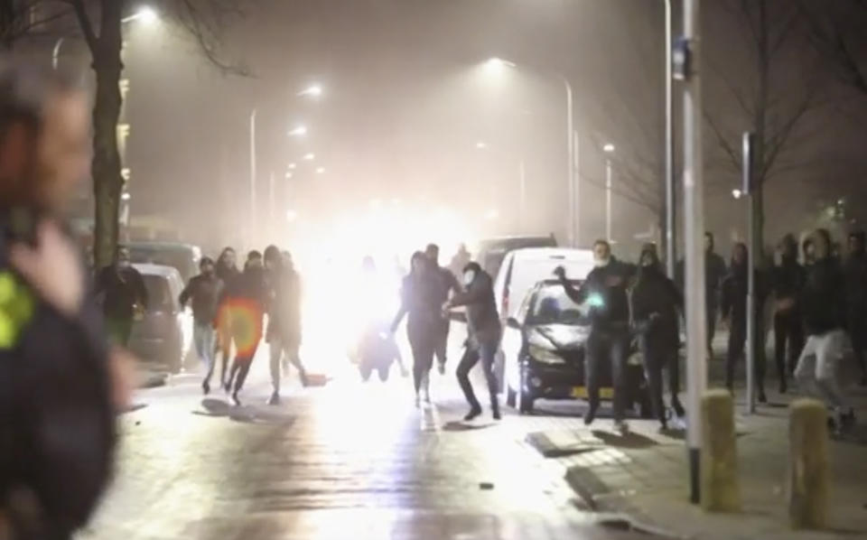 In this grab taken from video on Monday, Jan, 25, 2021, rioters throw stones at police, in Haarlem, Netherlands. Groups of youths have confronted police in several Dutch cities defying the country’s coronavirus curfew and throwing fireworks. Police in the port city of Rotterdam used a water cannon and tear gas in an attempt to disperse a crowd of rioters Monday night. (Mizzle Media via AP)