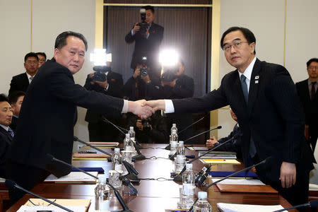 Head of the North Korean delegation, Ri Son Gwon shakes hands with South Korean counterpart Cho Myoung-gyon as they exchange documents after their meeting at the truce village of Panmunjom in the demilitarised zone separating the two Koreas, South Korea, January 9, 2018. REUTERS/Korea Pool