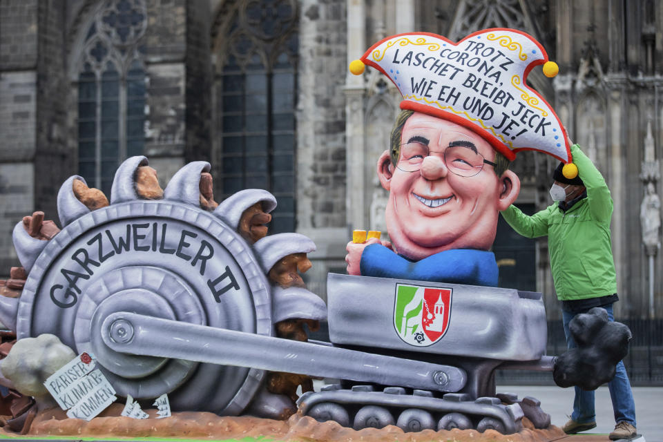 A carnival float designed by the environment organization Greenpeace and depicting North Rhine-Westphalia state governor Armin Laschet in a lignite mining dredger, stands in front of Cologne Cathedral in protest against his climate policy in Cologne, Germany, Monday, Feb. 15, 2021. The slogan on the hat reads : 'Despite Corona, Laschet is as mad as ever'. (Rolf Vennenbernd/dpa via AP)