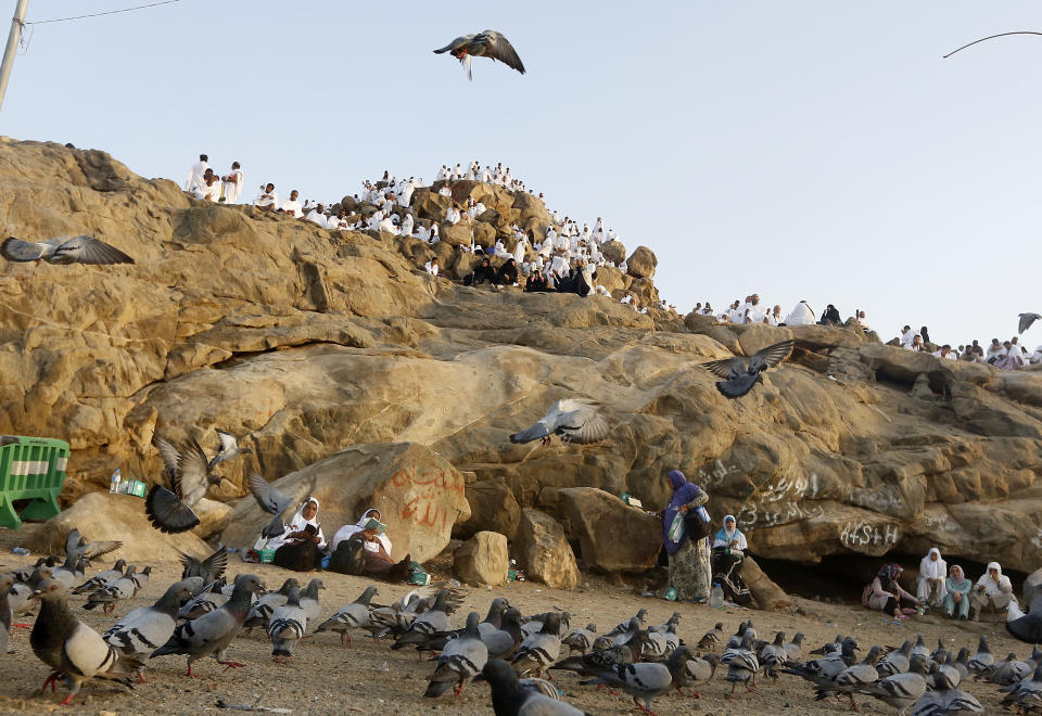 Pigeons fly as Muslim pilgrims pray on a rocky hill known as Mountain of Mercy, on the Plain of Arafat, during the annual hajj pilgrimage, near the holy city of Mecca, Saudi Arabia, Saturday, Aug. 10, 2019. More than 2 million pilgrims were gathered to perform initial rites of the hajj, an Islamic pilgrimage that takes the faithful along a path traversed by the Prophet Muhammad some 1,400 years ago. (AP Photo/Amr Nabil)