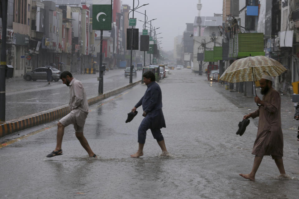 People cross a road during heavy rain in Peshawar, Pakistan, Monday, April 15, 2024. Lightening and heavy rains killed dozens of people, mostly farmers, across Pakistan in the past three days, officials said Monday, as authorities declared a state of emergency in the country's southwest following an overnight rainfall to avoid any further casualties and damages. (AP Photo/Muhammad Sajjad)