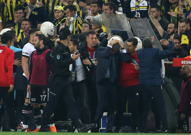 Besiktas head coach Senol Gunes (C) holds his head after being hit by an object during his team's Turkish Cup semi final against Fenerbahce