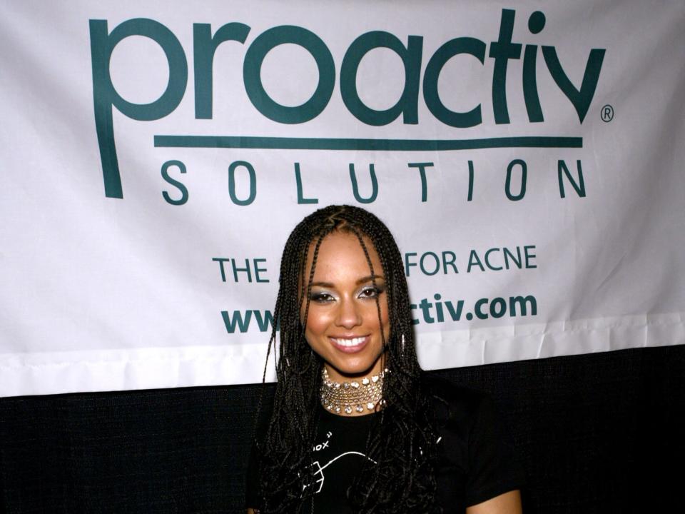 Alicia Keys posing in front of a Proactiv banner