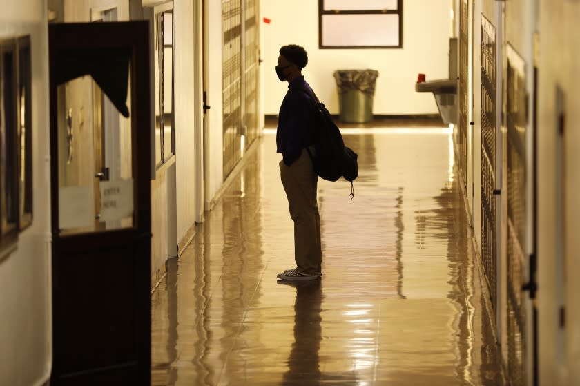 LONG BEACH, CA - MARCH 24: Freshman student Rene Arias on campus for the first time as students return to campus for in-person instruction at St. Anthony Catholic High School in Long Beach March 24, 2021. The students have not returned to campus since March 2020 due to the Covid-19 pandemic. The hybrid model that will be used at St. Anthony's will allow 60% of the school's 445 students to return for full-time, in-person instruction and splitting those to rotating days so roughly 134 students per day on campus, while also continuing remote learning for those who opt to remain at home. On campus Covid-19 safety measures include temperature checks, face masks, social distancing and plexiglass barriers around desks. President of St. Anthony High School Gina Maguire says they are "working to get all students back on campus by May." St. Anthony Catholic High School on Wednesday, March 24, 2021 in Long Beach, CA. (Al Seib / Los Angeles Times).