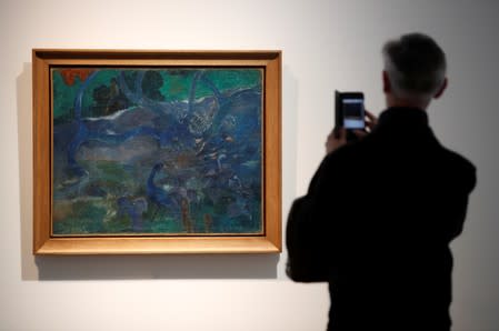 A man takes a picture of Paul Gauguin's "Te Bourao II" (The Purao Tree) painting (1897) at Artcurial's auction house in Paris