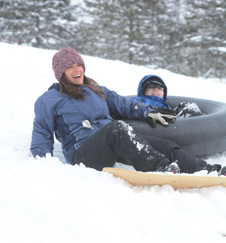 Cori Beckwith and William Newman, 9, both of Norwich, share a laugh after she ran off course on her snowboard hitting his inner tube at the Norwich Golf Course in Norwich Friday after the region's first major snowfall Jan. 7, 2022.