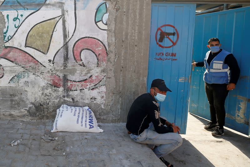 Palestinian worker stands at the entrance gate of an aid distribution center run by the United Nations Relief and Works Agency (UNRWA), at Beach refugee camp in Gaza City