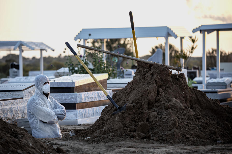 Member of Hevra Kadisha, an organization which prepares bodies of deceased Jews for burial according to Jewish tradition, waits during a funeral of a Jewish man who died from coronavirus in the costal city of Ashkelon, Israel, Thursday, April 2, 2020. (AP Photo/Tsafrir Abayov)