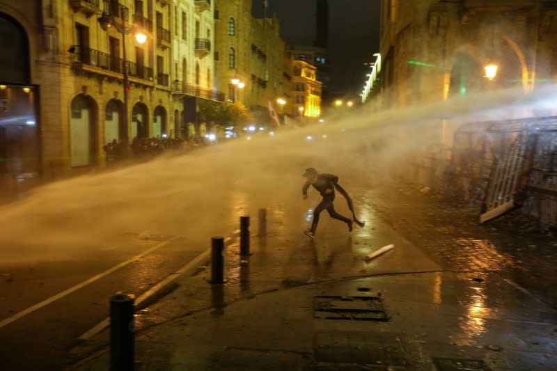 A demonstrator is hit by a water cannon during a protest against a ruling elite accused of steering Lebanon towards economic crisis in Beirut