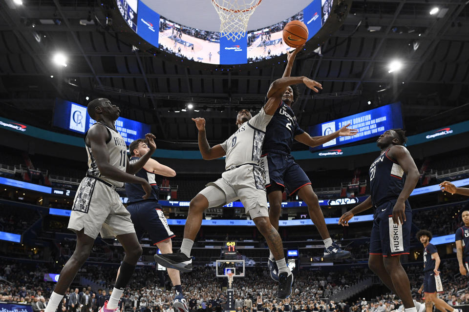 Connecticut guard Tristen Newton (2) fouls Georgetown guard Brandon Murray (0) during the second half of an NCAA college basketball game, Saturday, Feb. 4, 2023, in Washington. Connecticut won 68-62. (AP Photo/Nick Wass)