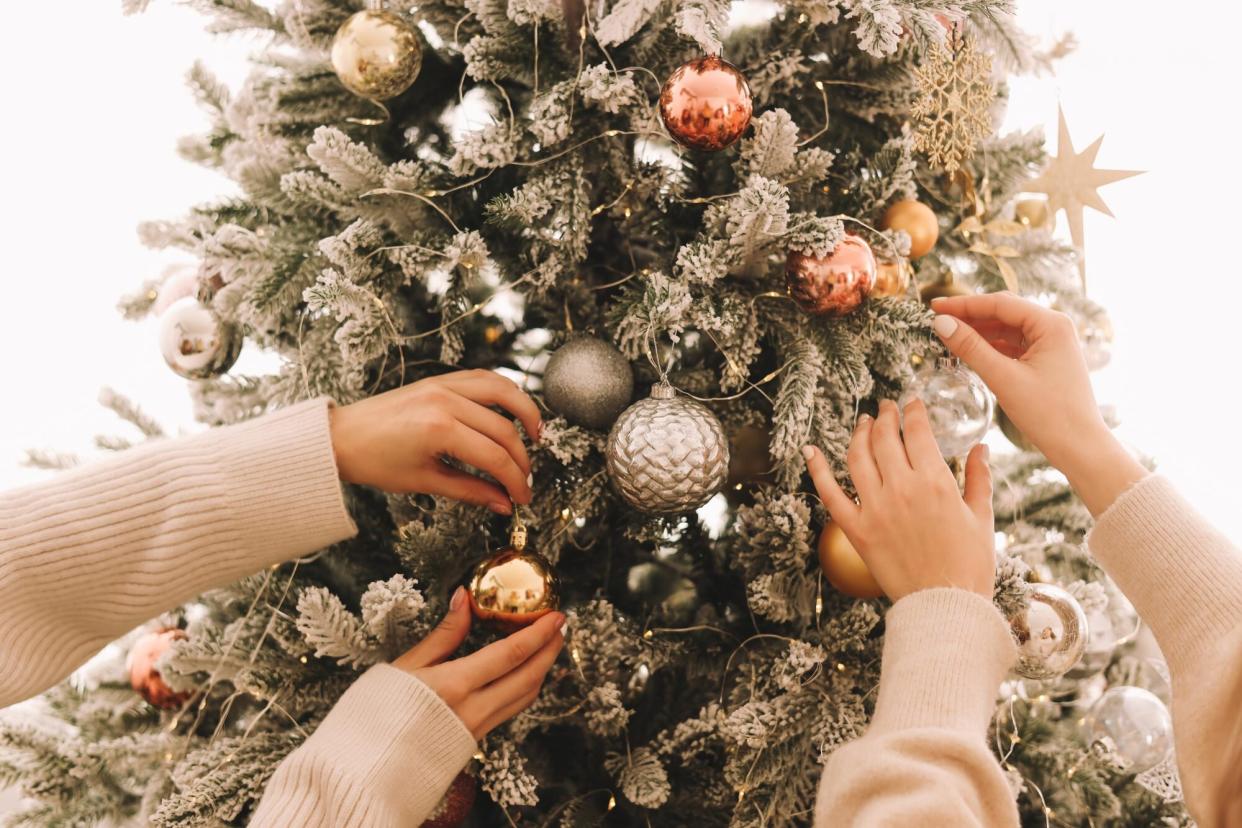 Two women putting ornaments on a christmas tree