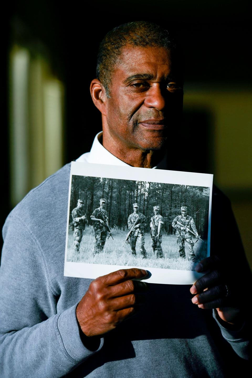 Alex Hicks Jr., photo editor of Gannett's SC publications, the News, Herald-Journal and Independent Mail, poses for a portrait with a photo of his fellow Navy photographers during a training mission in his home in Spartanburg, SC, on Wednesday, Nov. 8, 2023.