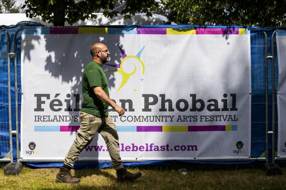 A man walks past a banner for Feile an Phobail, also known as the West Belfast Festival, in the Falls Park. (PA) (PA Wire)