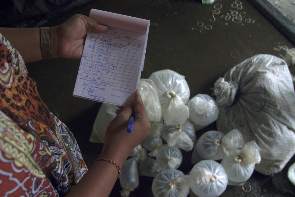 A worker checks a sort and order list at middle man area in Les, Bali, Indonesia, on April 10, 2021. (AP Photo/Alex Lindbloom)