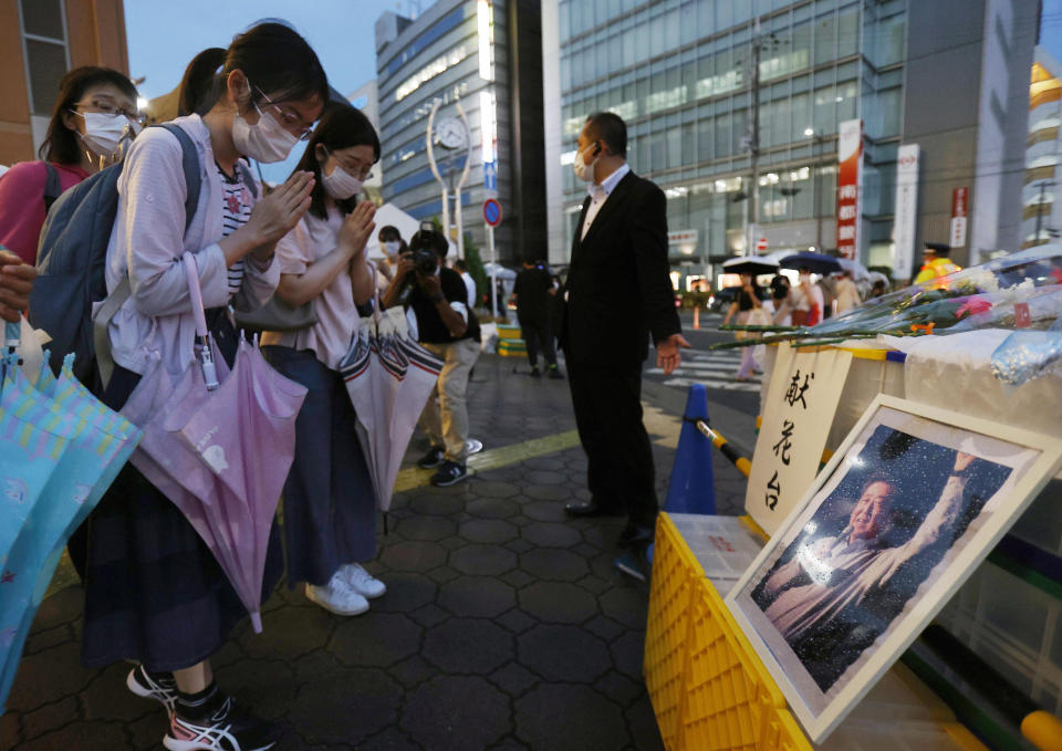 A photo of former Prime Minister Shinzo Abe is displayed on a makeshift memorial near the scene where Abe was fatally shot while delivering his speech to support a Liberal Democratic Party's candidate on Friday, in Nara, Saturday, July 9, 2022. (Yosuke Mizuno/Kyodo News via AP)