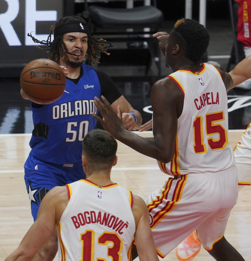Orlando Magic guard Cole Anthony (50) looks for an opening past Atlanta Hawks guard Bogdan Bogdanovic (13) and center Clint Capela (15) in the first half of an NBA basketball game Thursday, May 13, 2021 in Atlanta. (AP Photo/Tami Chappel)